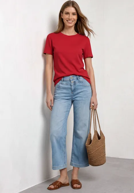 T-Shirt mit gerafftem Ärmel salsa red Frau in rotem T-Shirt, weitem blauen Jeans, braunen Sandalen und Korbtasche an weißer Wand.