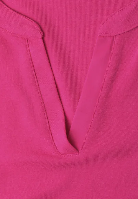 Nahaufnahme eines pinkfarbenen Oberteils mit V-förmigem Ausschnitt und sichtbarer Naht.