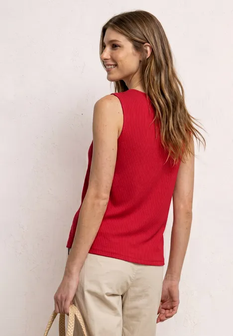 Frau von hinten in rotem ärmellosem Top, heller Hose und Tasche