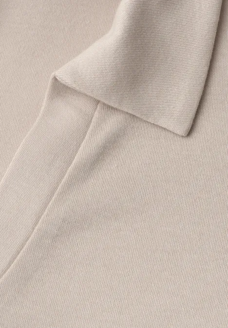Poloshirt met elastische tailleband clay sand Close-up van een beige gebreide sjaal op een bijpassende gebreide achtergrond.