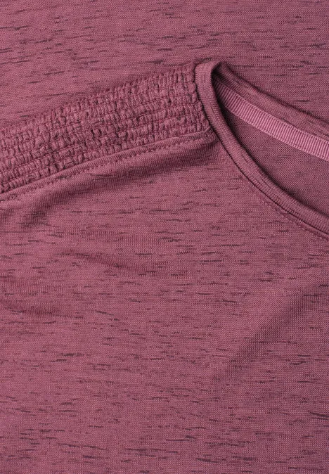 Nahaufnahme eines bordeauxfarbenen T-Shirts mit sichtbarer Naht am Kragen.
