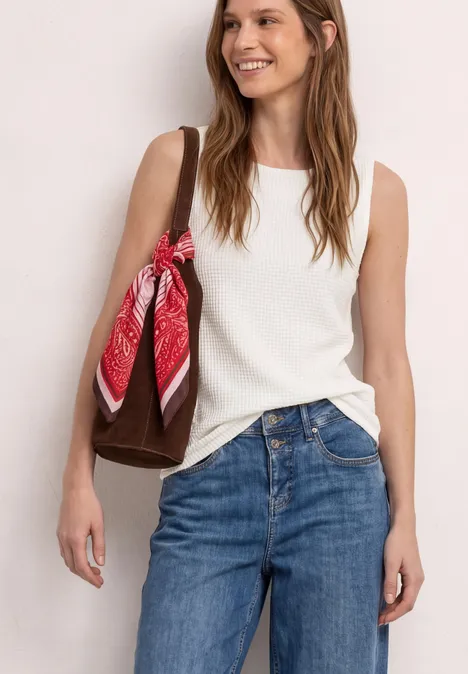 2-in-1 top van mesh met boothals off white Vrouw met een witte mouwloze top, blauwe jeans en een bruine tas met een rood sjaaltje.