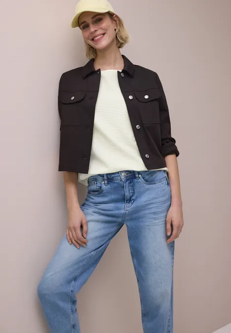 Shirt met structuur in effen kleur off white Vrouw draagt zwart kort jasje, wit topje en blauwe jeans.