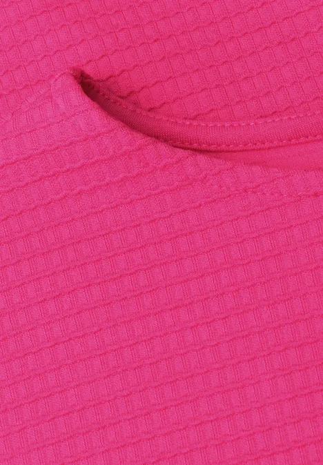 Nahaufnahme eines pinken Textilstücks mit Waffelmuster und abgerundeter Öffnung