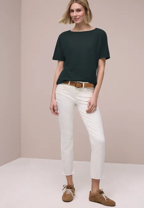 Shirt met structuur in effen kleur deep bound green Vrouw in zwart T-shirt, witte jeans, bruine riem en schoenen poseert voor een neutrale achtergrond.