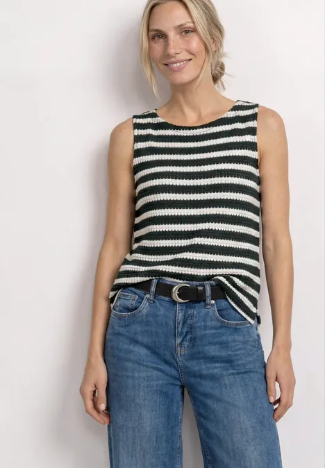 Femme portant un débardeur rayé noir et blanc avec un jean bleu et ceinture.