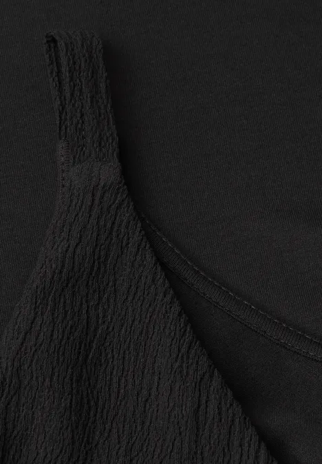 Top in structuurmix Black Close-up van een zwart topje met gekreukte textuur.