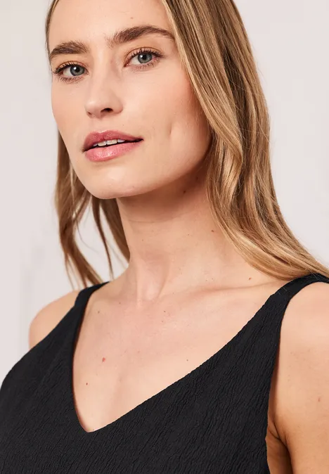 Top in structuurmix Black Portret van een vrouw met blond haar in een zwart mouwloos topje met V-hals.