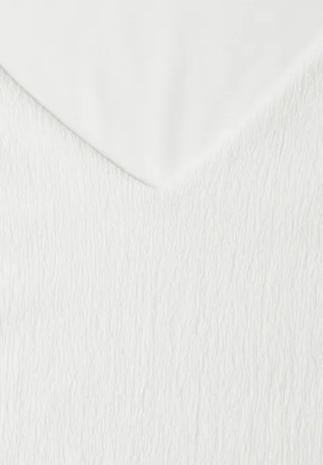 Nahaufnahme einer weißen, strukturierten Stoffoberfläche mit V-förmiger Falte.