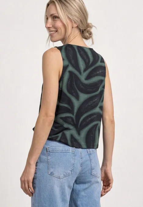 Vrouw van achteren in een zwart topje met groen motief en een blauwe spijkerbroek.