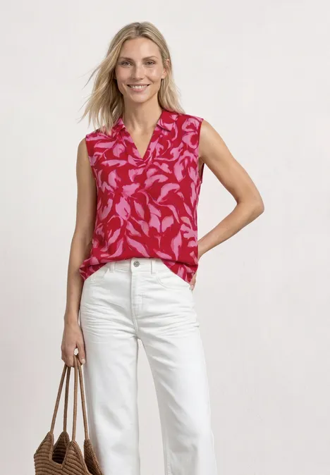 Top avec col fendu et mélange de structures salsa red Haut sans manches rouge à motif floral, jean blanc et sac cabas beige.