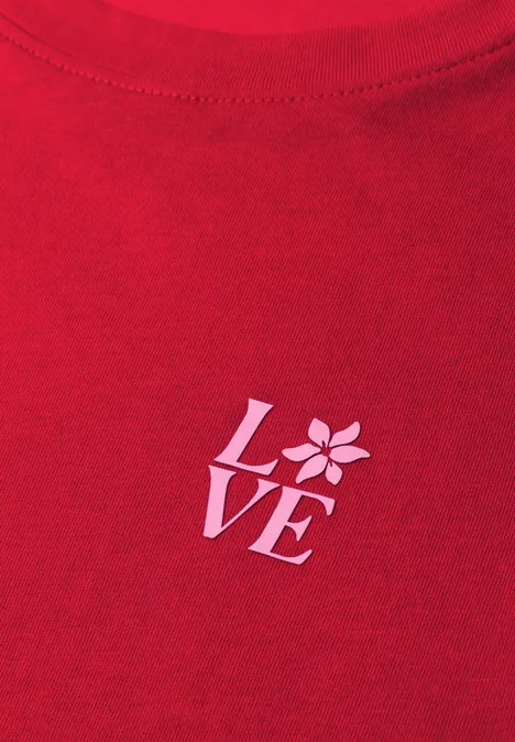 Rotes T-Shirt mit weißem LOVE-Print, wobei das O durch eine stilisierte Blüte ersetzt ist.