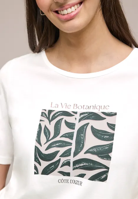 Weißes T-Shirt mit stilisiertem Blattmuster und Schriftzug „La Vie Botanique COTE D'AZUR“.