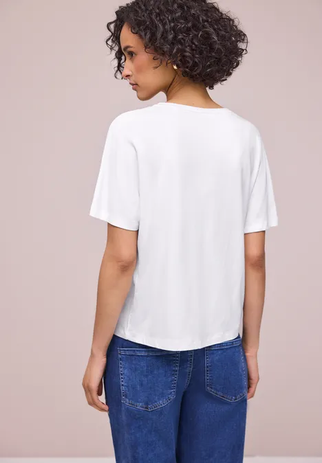 Een persoon van achteren in een wit t-shirt en blauwe spijkerbroek.