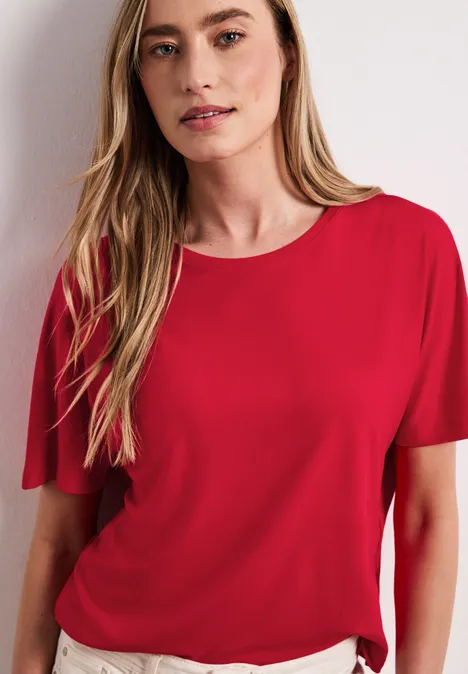 Vrouw in rood T-shirt voor een witte achtergrond.