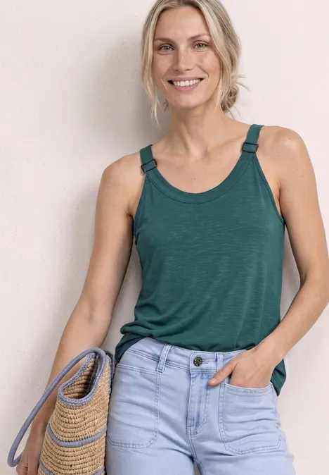 Top mit V-Neck und Deko-Detail mediterra green Person mit grünem ärmellosem Top und hellblauer Jeans hält eine geflochtene Tasche aus Stroh.