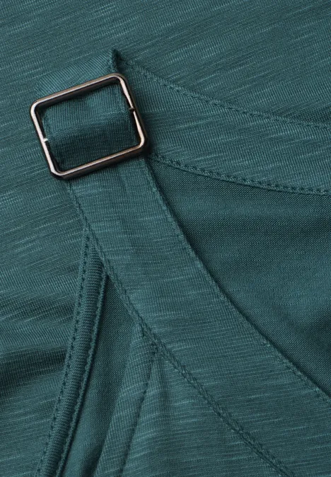 Top mit V-Neck und Deko-Detail mediterra green Nahaufnahme eines tealfarbenen Stoffgurts mit verstellbarem Metallschieber an einem Kleidungsstück.