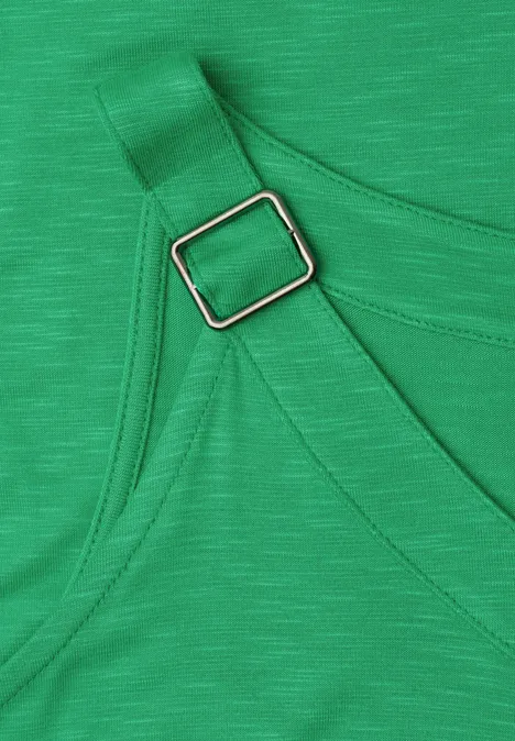 Close-up van groene stof met verstelbare band en zilverkleurige rechthoekige gesp.