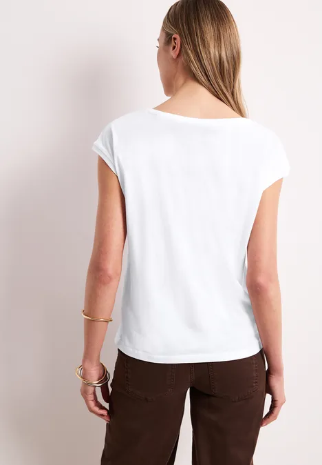 Vrouw van achter gezien met een wit t-shirt en een bruine broek.