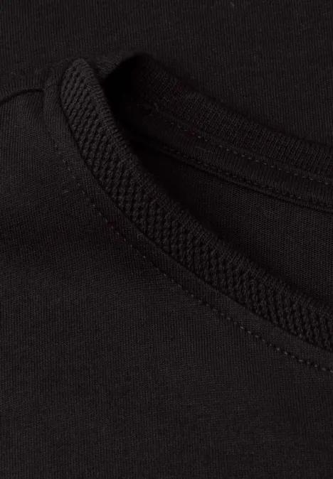 Close-up van een zwart T-shirt met ronde hals en duidelijke, nette naad.