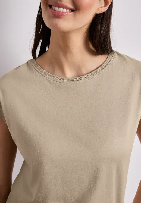 Shirt mit Boatneck und Deko-Detail timeless beige Eine lächelnde Frau in ärmellosem, beigem Top.