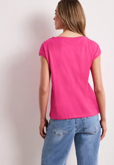 Eine Frau von hinten in pinkem T-Shirt und blauen Jeans.