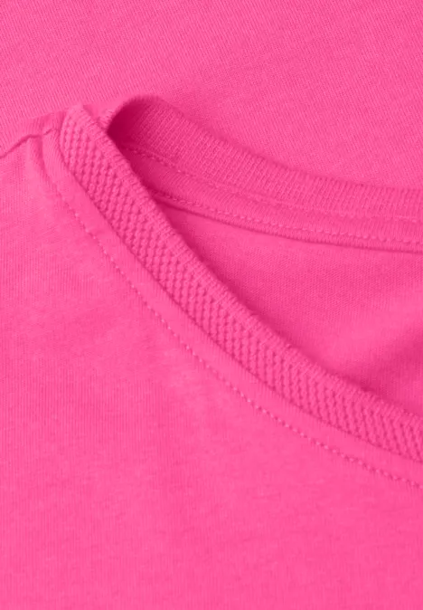 Nahaufnahme eines pinkfarbenen T-Shirt-Ausschnitts mit sichtbarer Naht und weichem Baumwollstoff.