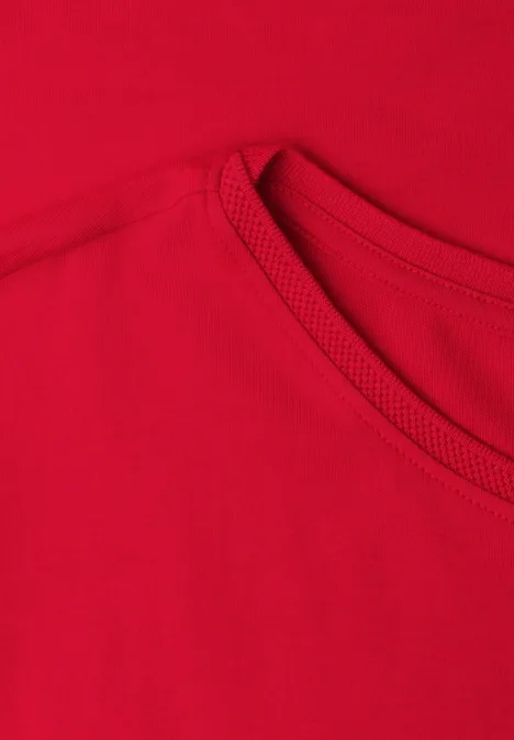 Close-up van een rood T-shirt met zichtbare halslijn en naden.