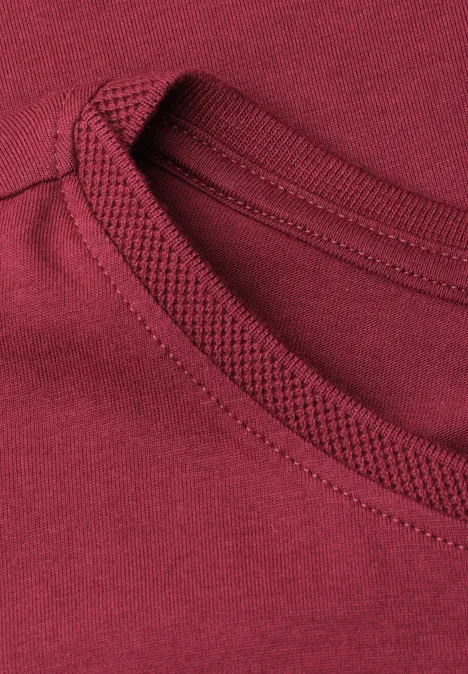 Close-up van de bordeauxrode T-shirthals met nette stiksels en hoogwaardige afwerking.