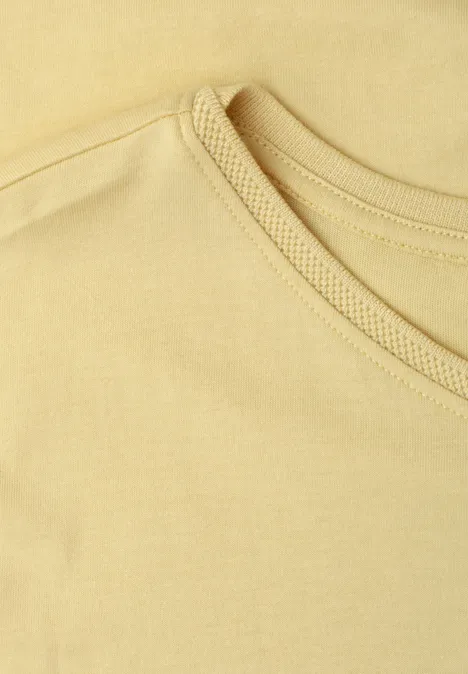 Das Bild zeigt einen Nahaufnahme-Ausschnitt eines hellgelben T-Shirts mit Rundhalsausschnitt.