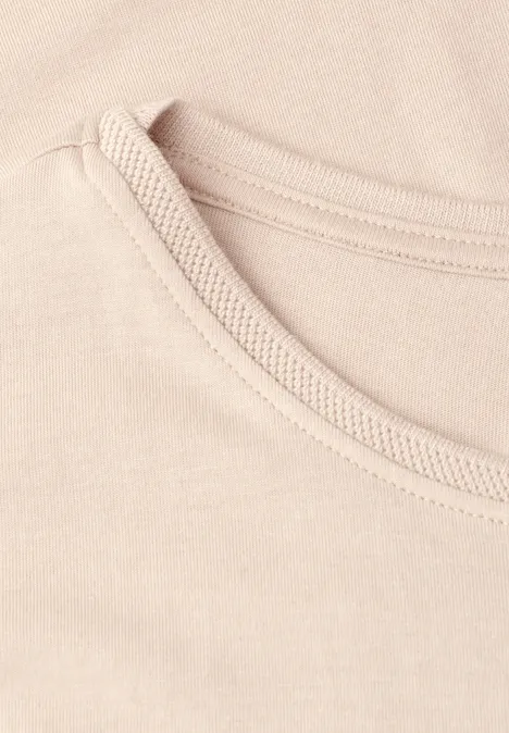 Close-up van een lichtbeige ronde hals van een T-shirt.