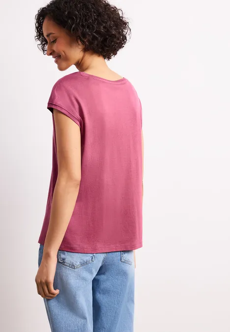 Vrouw van achteren in een roze t-shirt en lichtblauwe jeans.
