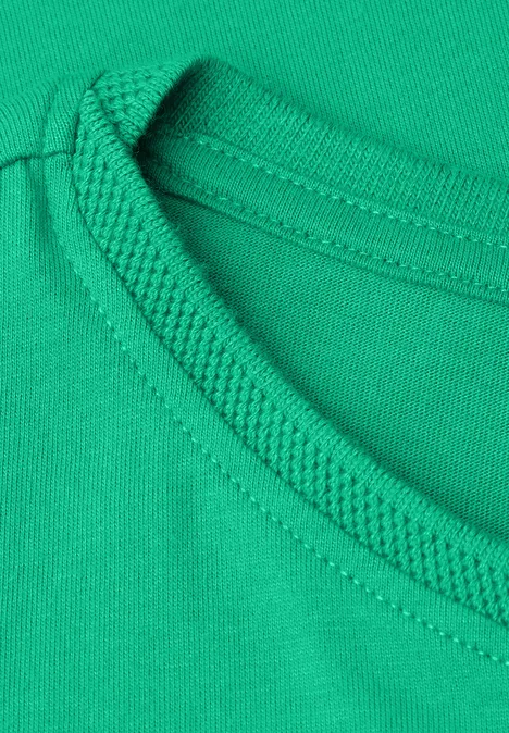 Close-up van een groene T-shirthals met versterkte naad
