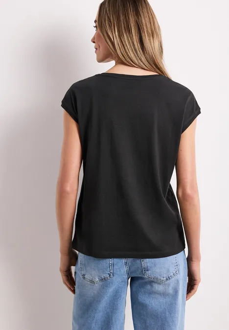 Vrouw van achteren, met een zwart shirt en een blauwe spijkerbroek.