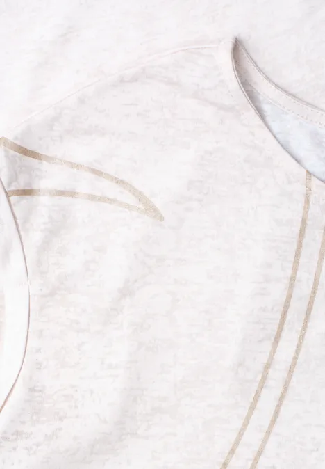 Gros plan d’un t-shirt clair avec motif de lignes dorées délicates sur un tissu doux.