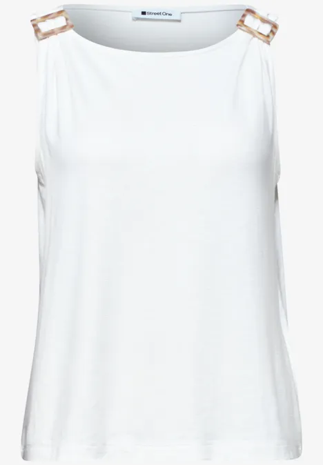 Wit mouwloos topje met gouden gespen op de schouders.