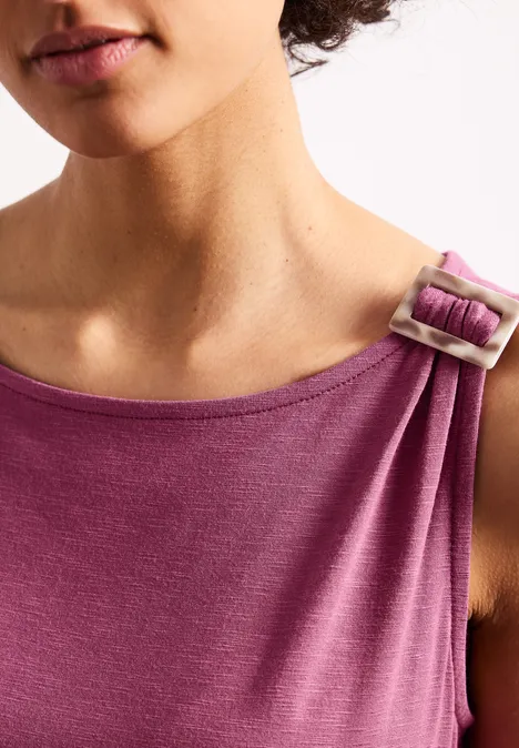 Close-up van een mouwloze paarse top met ringgesp op de schouder gedragen door een vrouwelijk bovenlichaam.