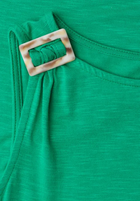 Groene stoffen band met een vierkante, lichte gesp op de schouder.