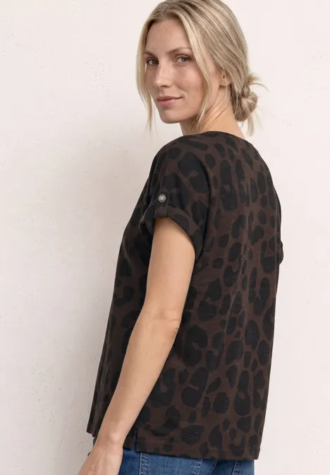 Zijaanzicht van een vrouw met blond opgestoken haar, in een donkerbruin t-shirt met panterprint voor lichte achtergrond