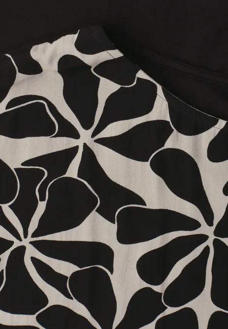 Close-up van een kledingstuk met een zwart-wit abstract bloempatroon.