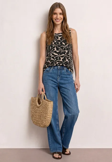 Top mit Rundhals und Schulterdetail Black Frau trägt weite Jeans, bedrucktes Top und hält eine geflochtene Handtasche.