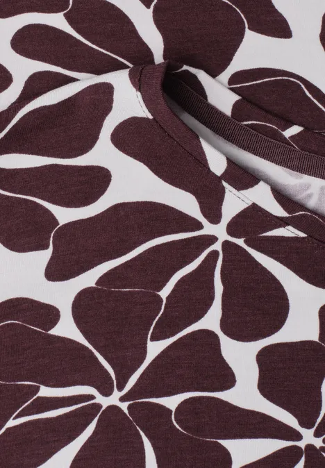 Weißer Stoff mit dunkelrotem, großem Blumenmuster und kleinem Schlitz mit Knoten.