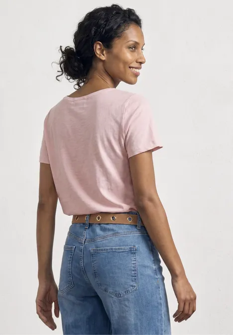 Frau von hinten in rosa T-Shirt und blauen Jeans mit Ledergürtel.