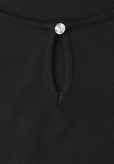 Schwarzes Shirt mit kleinem Tropfenausschnitt und funkelndem Kristallknopf.