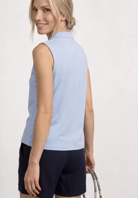 Vrouw van achteren in lichtblauwe mouwloze top, donkere short en handtas.