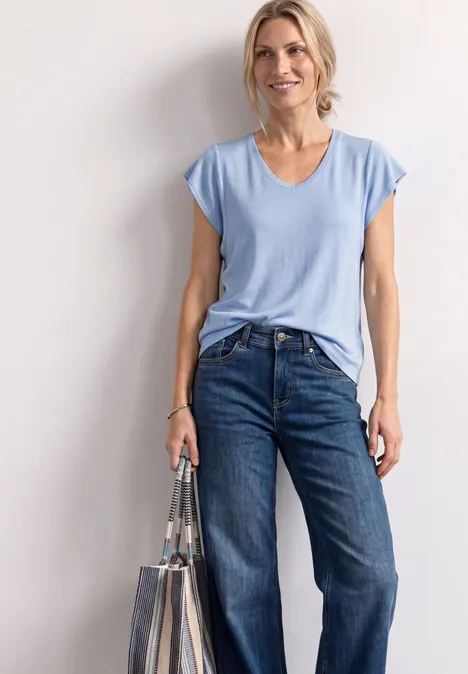 Shirt met korte volantmouwen cashmere blue Vrouw met lichtblauw T-shirt, spijkerbroek en een doorzichtige tas.
