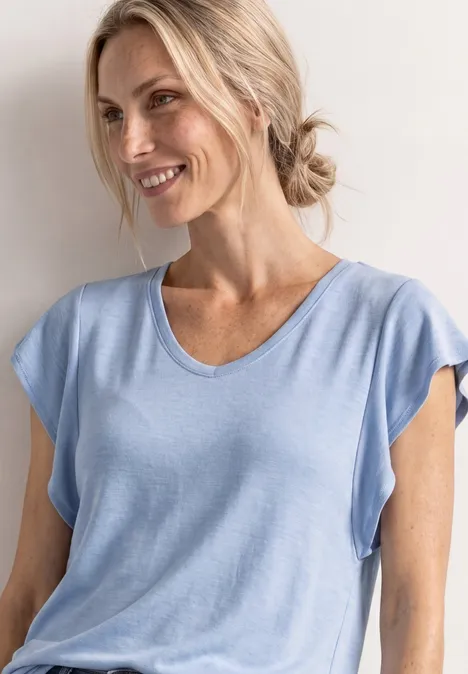 Shirt met korte volantmouwen cashmere blue Een vrouw met blond haar in een knot draagt een lichtblauw t-shirt en kijkt opzij.