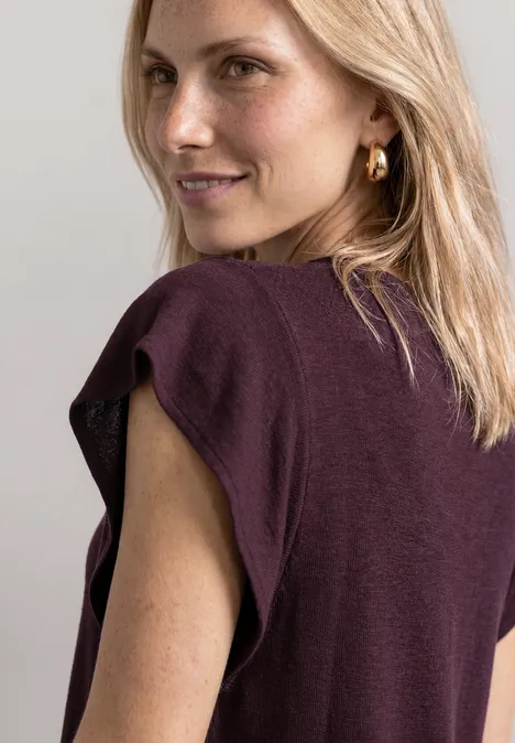 Shirt mit kurzen Volant-Ärmeln rustic rouge Blonde Frau von hinten in ärmellosem violettem Top und goldenen Ohrringen.