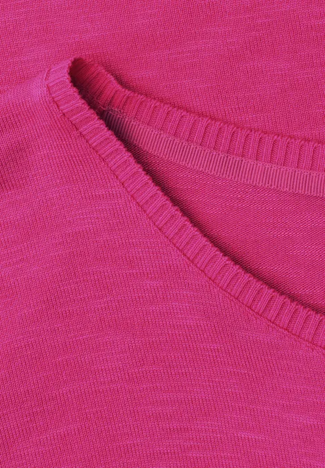 Nahaufnahme eines pinken Strickstoffs mit feiner Maschenstruktur und abgerundetem Ausschnitt