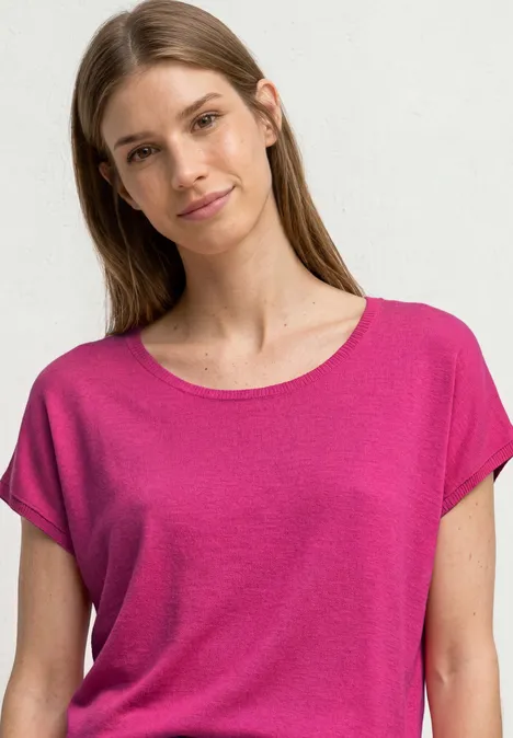 Eine Frau in pinkem T-Shirt vor weißem Hintergrund.